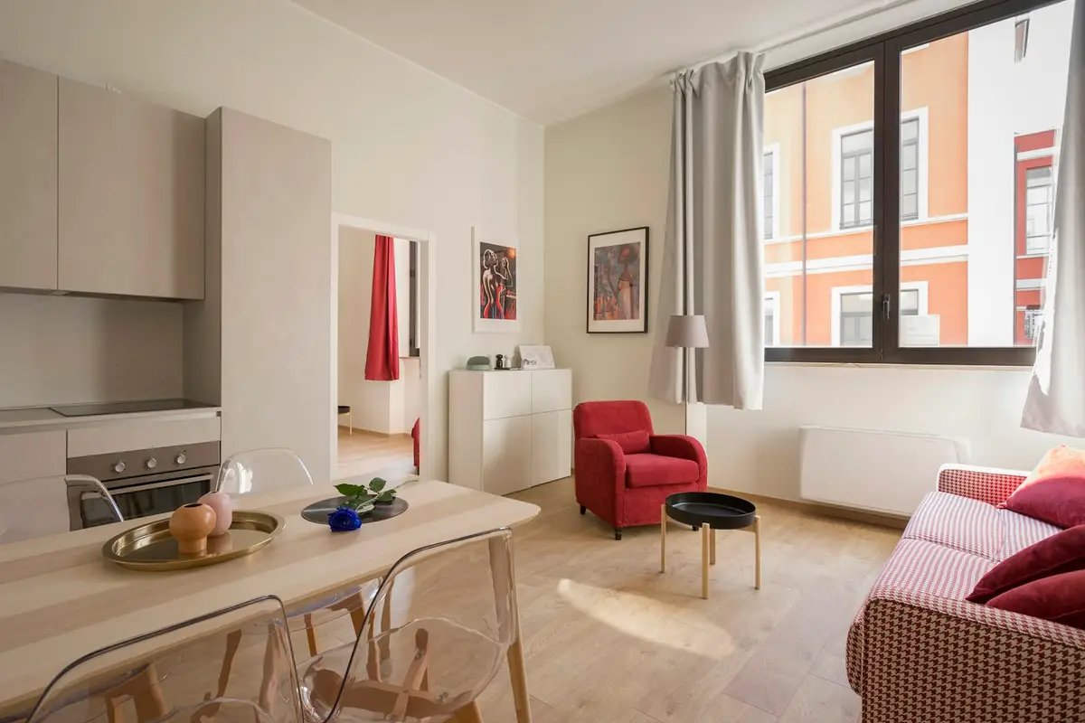 A bright living room with a sofa and dining table near large windows