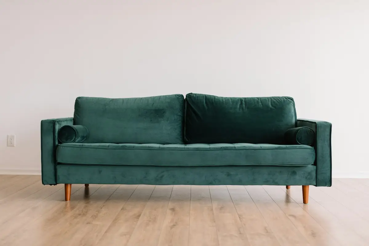 A green sofa in a bright, empty room
