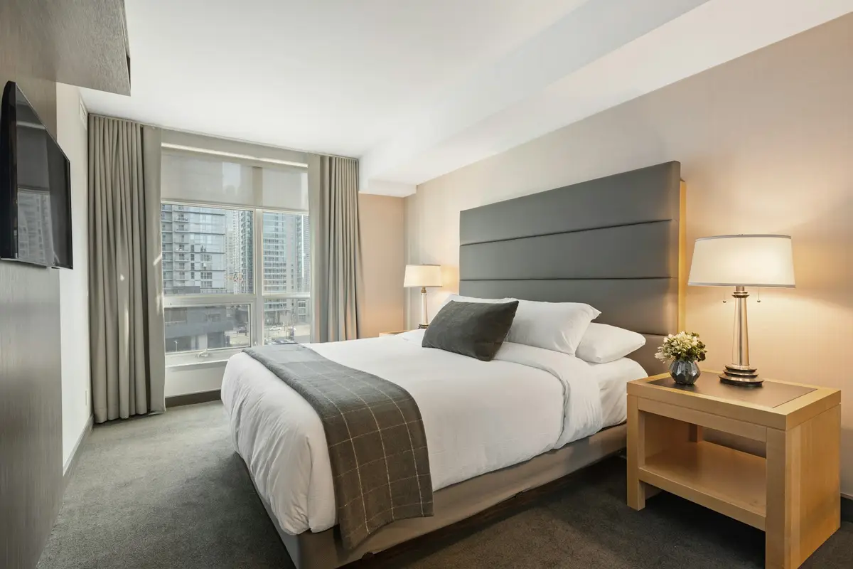 A neat single room with a bed, lamp and desk
