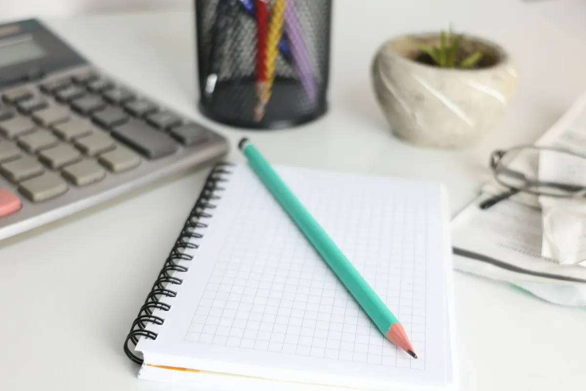 A calculator, a notebook and a pencil on a desk