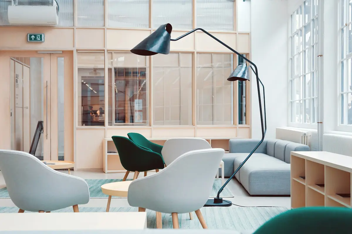 An office lounge with chairs, desks and large windows