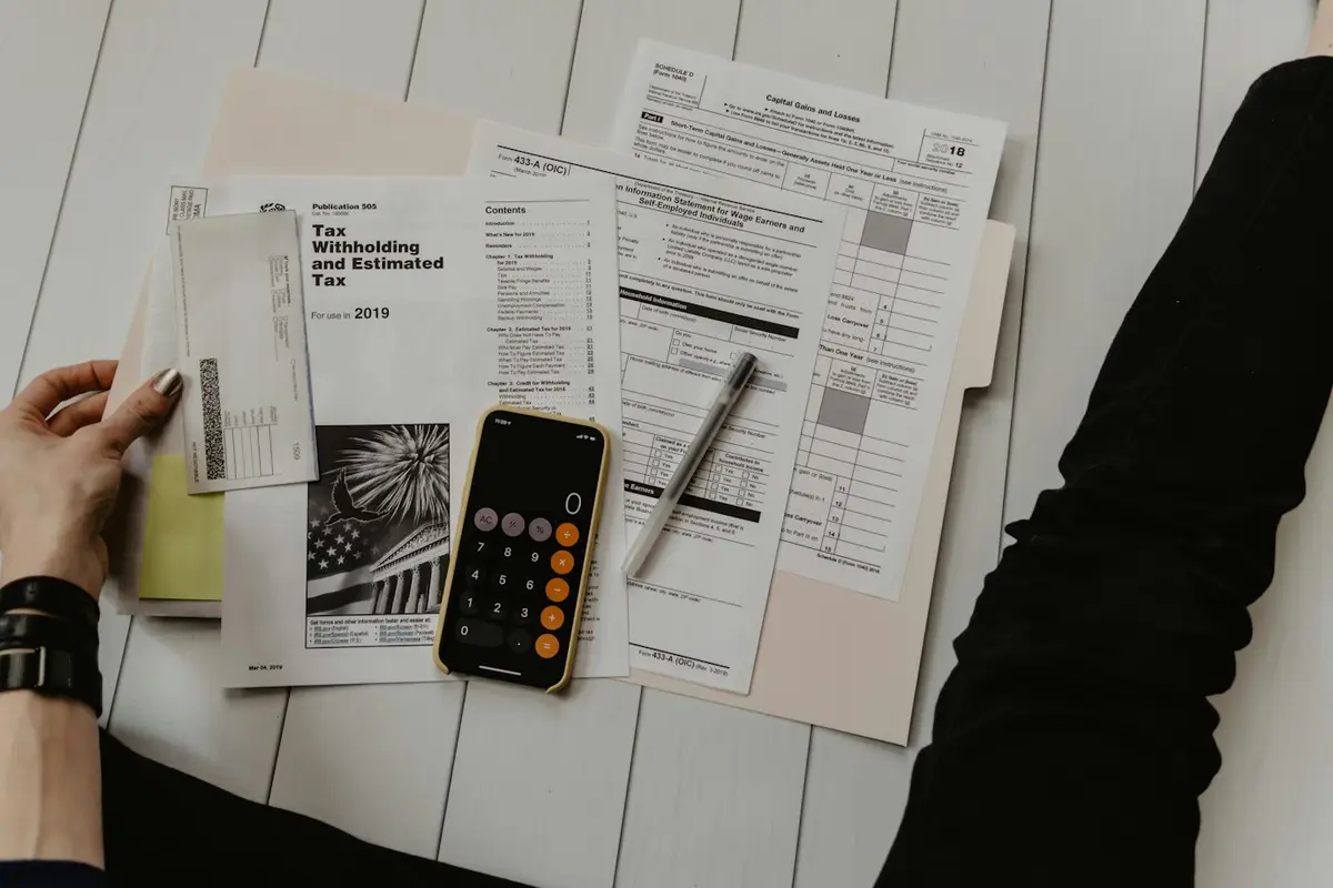 Papers, a calculator and a pen on a white desk