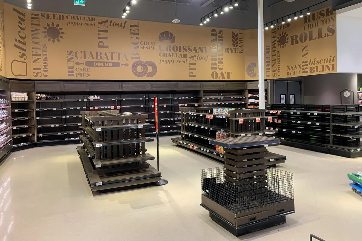 The inside of an empty retail shop with shelving units and a bright ceiling