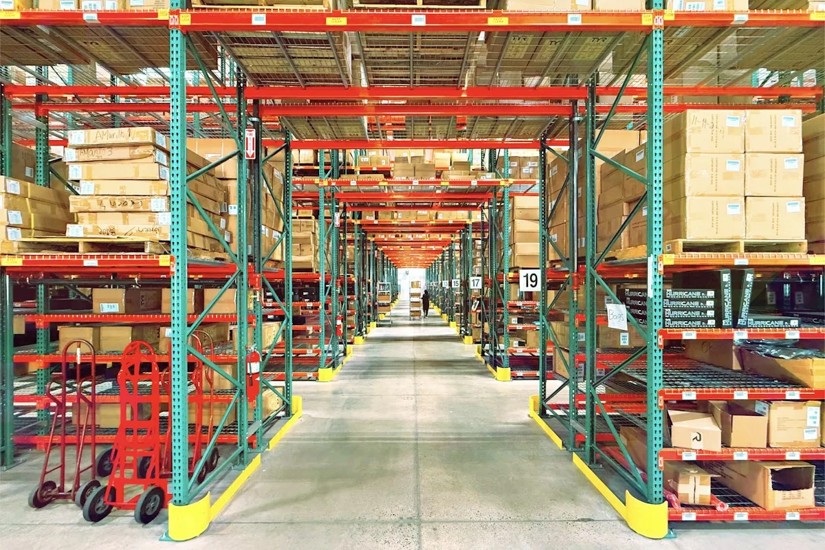 A large warehouse with tall shelving and a worker in the distance
